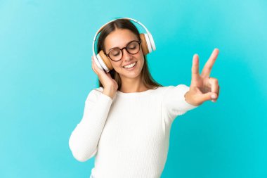 Soyutlanmış mavi arka plan müzik dinleyen ve şarkı söyleyen genç bir kadın.