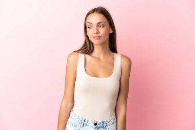 Soyutlanmış pembe arka planı olan genç bir kadın.