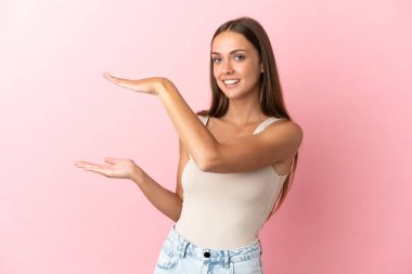 İzole edilmiş pembe arka plan üzerinde genç bir kadın ilan vermek için kopyalama alanı tutuyor