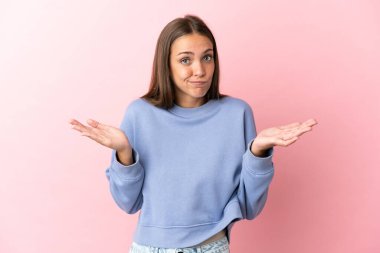 Soyutlanmış pembe arka planı olan genç bir kadın ellerini kaldırırken şüpheye düşüyor.