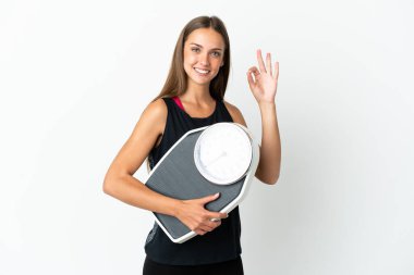 İzole edilmiş beyaz arka plan üzerinde genç bir kadın elinde bir tartı makinesi tutuyor ve 