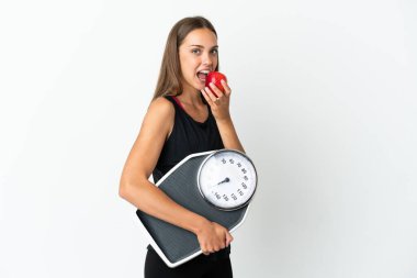 Tartı makinesi ve elmasıyla izole edilmiş beyaz arka planı olan genç bir kadın.