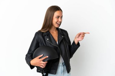 İzole edilmiş beyaz arkaplan üzerinde motosiklet kaskı olan bir kadın parmak göstererek bir ürün sunuyor.