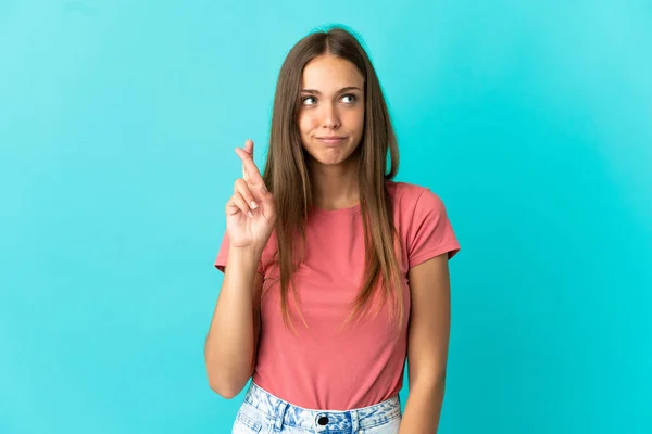 Young woman over isolated blue background with fingers crossing and wishing the best