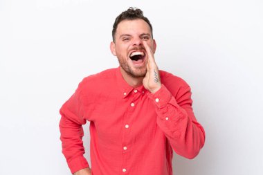 Beyaz arka planda izole edilmiş genç Brezilyalı adam ağzı açık bağırıyor.