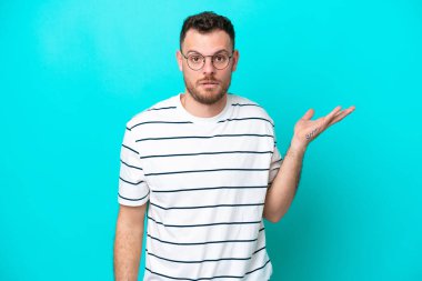 Mavi arka planda izole edilmiş Brezilyalı genç şüpheli hareketler yapıyor.