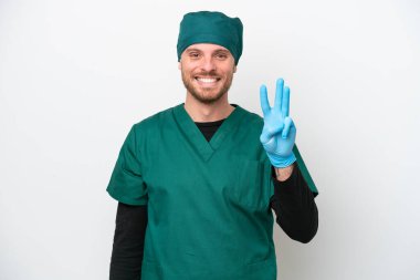 Yeşil üniformalı cerrah beyaz arka planda izole edilmiş mutlu ve parmaklarıyla üçe kadar sayıyor.