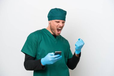 Cerrah Brezilyalı yeşil üniformalı adam beyaz arka planda izole edilmiş ve telefon zafer pozisyonunda.