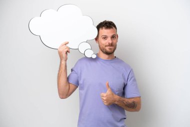 Beyaz arka planda izole edilmiş genç Brezilyalı bir adam düşünme balonunu başparmağıyla tutuyor.