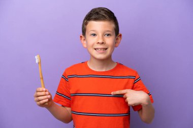 Mor arka planda diş fırçalayan küçük çocuk şaşırmış yüz ifadesi ile