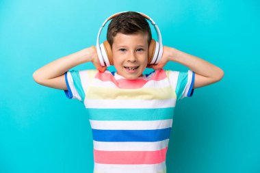 Küçük çocuk mavi arka planda izole edilmiş müzik dinliyor.