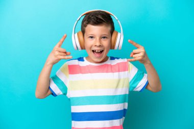 Little boy isolated on blue background listening music making rock gesture
