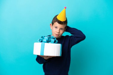 Küçük çocuk mavi arka planda izole edilmiş bir doğum günü pastası tutuyor.