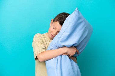 Mavi arka planda pijamalı küçük bir çocuk.