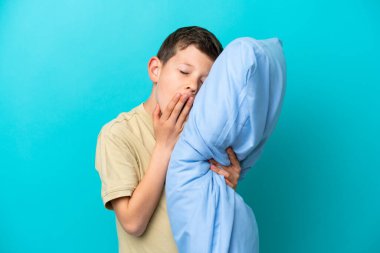 Mavi arka planda pijamalı küçük bir çocuk.