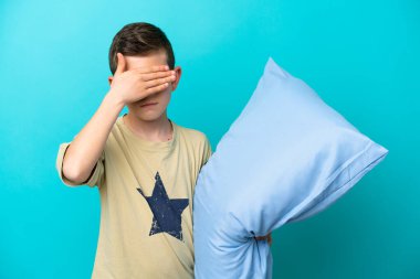 Pijamalı küçük bir çocuk mavi arka planda tek başına, gözleri elleriyle kapatıyor. Bir şey görmek istemiyorum.