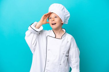Küçük aşçı çocuk mavi arka planda izole edilmiş, gülümsüyor.