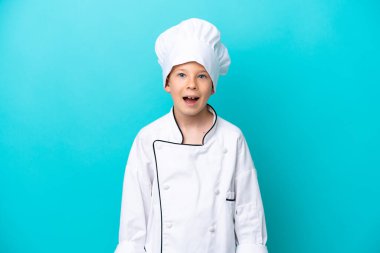 Küçük aşçı çocuk mavi arka planda mahsur kalmış ve yüzünde sürpriz bir ifade var.