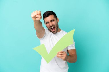 Mavi arka planda izole edilmiş yakışıklı beyaz adam elinde bir çek ikonu tutuyor ve zaferi kutluyor.