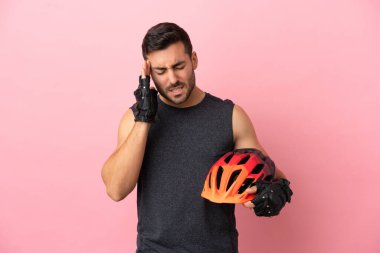 Pembe arka planda başağrısı olan genç bir bisikletçi.