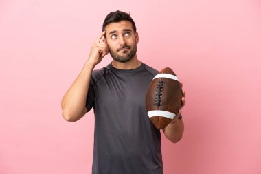 Pembe arka planda ragbi oynayan beyaz bir genç. Şüpheleri ve düşünceleri var.