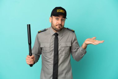 Mavi arka planda yalnız kalan genç güvenlik görevlisi ellerini kaldırırken şüpheye düşüyor