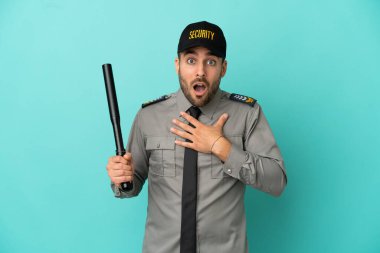 Mavi arka planda izole edilmiş genç güvenlik görevlisi sağa bakarken şaşırmış ve şok olmuştu.