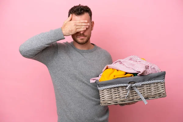 Genç Brezilyalı bir adam pembe arka planda, elleri ve gözleri kaplayan bir çamaşır sepeti tutuyor. Bir şey görmek istemiyorum.