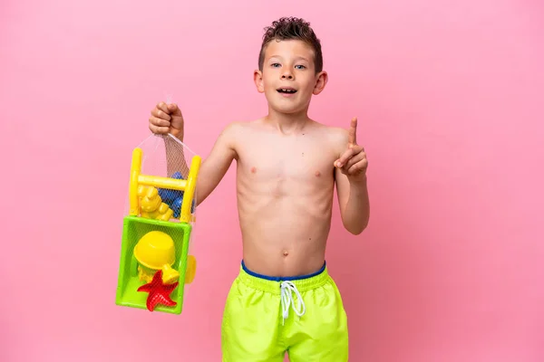 Little Caucasian Boy Holding Beach Toys Isolated Pink Background Pointing —  Fotos de Stock