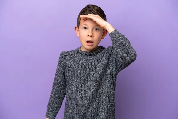 一个被紫色背景隔离的小男孩一边看着前方一边惊讶地做着手势 — 图库照片