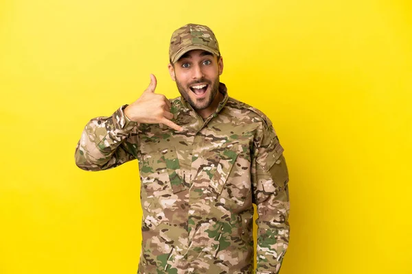 Military man isolated on yellow background making phone gesture. Call me back sign