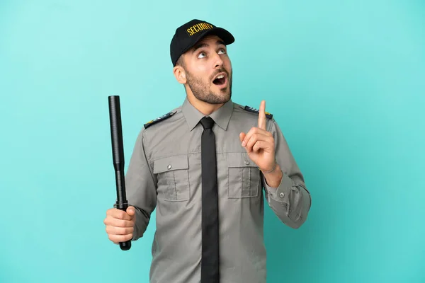 Young security man isolated on blue background thinking an idea pointing the finger up