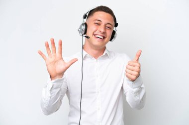 Telemarketer Brazilian man working with a headset isolated on white background counting six with fingers