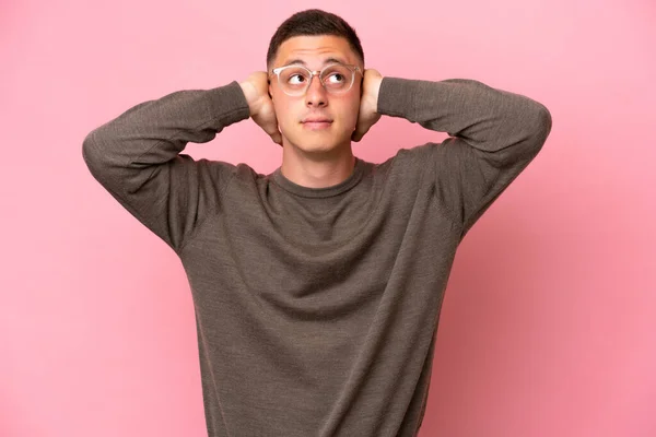 若いブラジル人男性ピンクの背景に不満とカバー耳に隔離 — ストック写真
