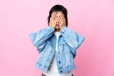 Genç Uruguaylı kadın izole pembe arka planda gözlerini elleriyle kapatıyor.