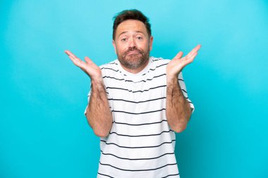 Mavi arka planda izole edilmiş orta yaşlı beyaz bir adam şüpheli hareketlerde bulunuyor.