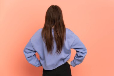 Young Ukrainian girl isolated on pink background in back position