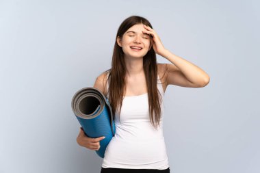 Ukraynalı genç sporcu kız, elinde minderle yoga derslerine gidip gülümsüyor.