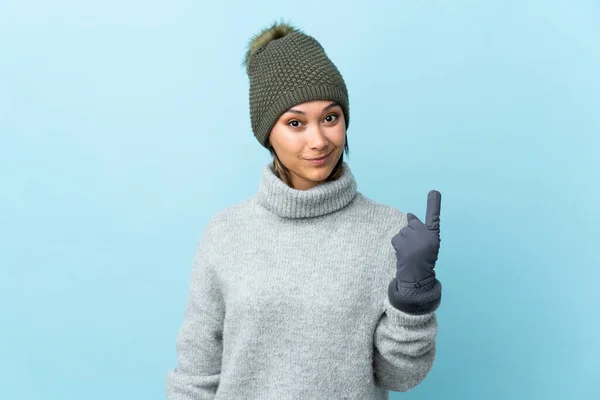 年轻的乌拉圭姑娘 戴着一顶蓝色背景的冬帽 用食指指尖着 真是个好主意 — 图库照片