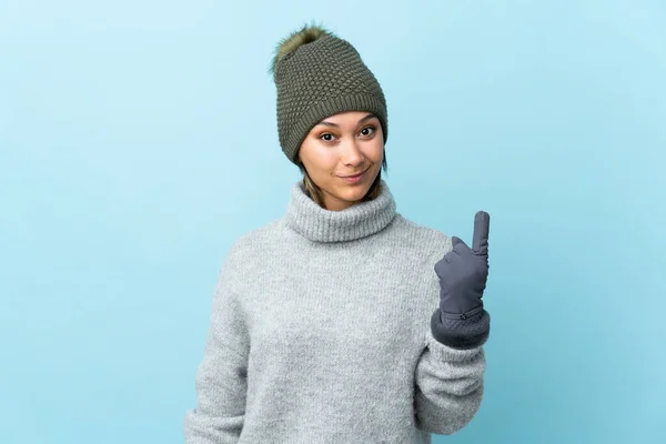 Jovem Uruguaia Com Chapéu Inverno Isolado Fundo Azul Apontando Com — Fotografia de Stock