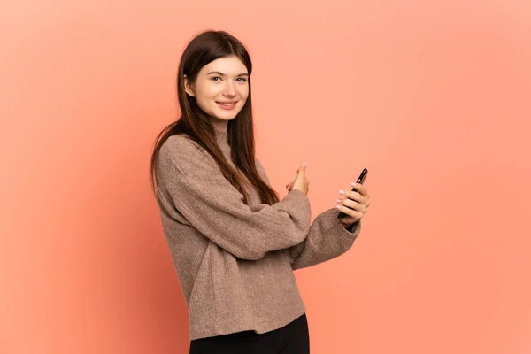 Young Ukrainian Girl Isolated Pink Background Using Mobile Phone Pointing —  Fotos de Stock