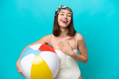 Plaj topu tutan genç Ukraynalı kadın mavi arka planda izole edilmiş, çok gülümsüyor.