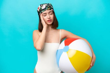 Elinde plaj topu tutan genç Ukraynalı kadın mavi arka planda baş ağrısı ile izole edilmiş.