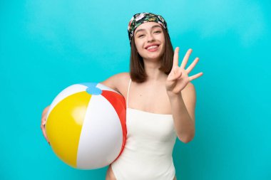 Mavi arka planda kumsal topu tutan genç Ukraynalı kadın mutlu ve parmaklarıyla dört tane sayıyor.