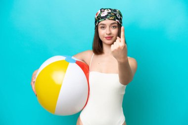 Plaj topu tutan genç Ukraynalı kadın mavi arka planda izole edilmiş bir şekilde el hareketi yapıyor.