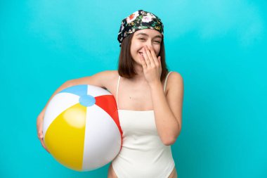 Genç Ukraynalı bir kadın elinde plaj topu tutarken mavi arka planda izole edilmiş mutlu ve gülümsüyor.