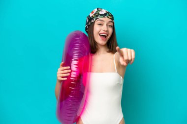 Mavi arka planda şişme yatak tutan genç Ukraynalı kadın mutlu bir ifadeyle öne bakıyor.