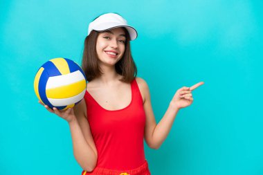 Genç Ukraynalı bir kadın, plajda voleybol oynuyor. Mavi arka planda izole edilmiş, parmağıyla yan tarafı işaret ediyor.