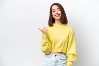 Beyaz arka planda izole edilmiş genç Ukraynalı kadın bir ürünü sunmak için kenarı işaret ediyor