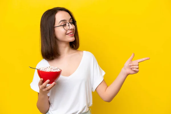 Jovem Ucraniano Segurando Uma Tigela Cereais Isolado Fundo Amarelo Apontando — Fotografia de Stock